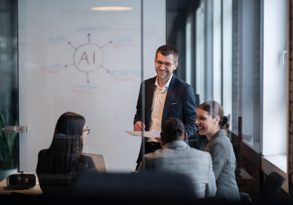Diverse business team in a modern office during a meeting, discussing artificial intelligence strategy. Concept of AI innovation, teamwork, leadership, corporate planning, professional collaboration.