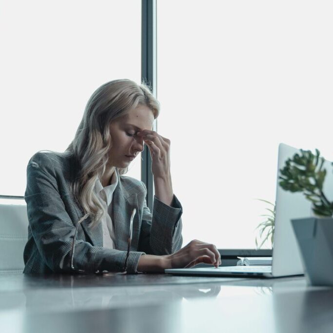 Stressed businesswoman looking at her laptop, suggesting her business is struggling and she may need business recovery support.
